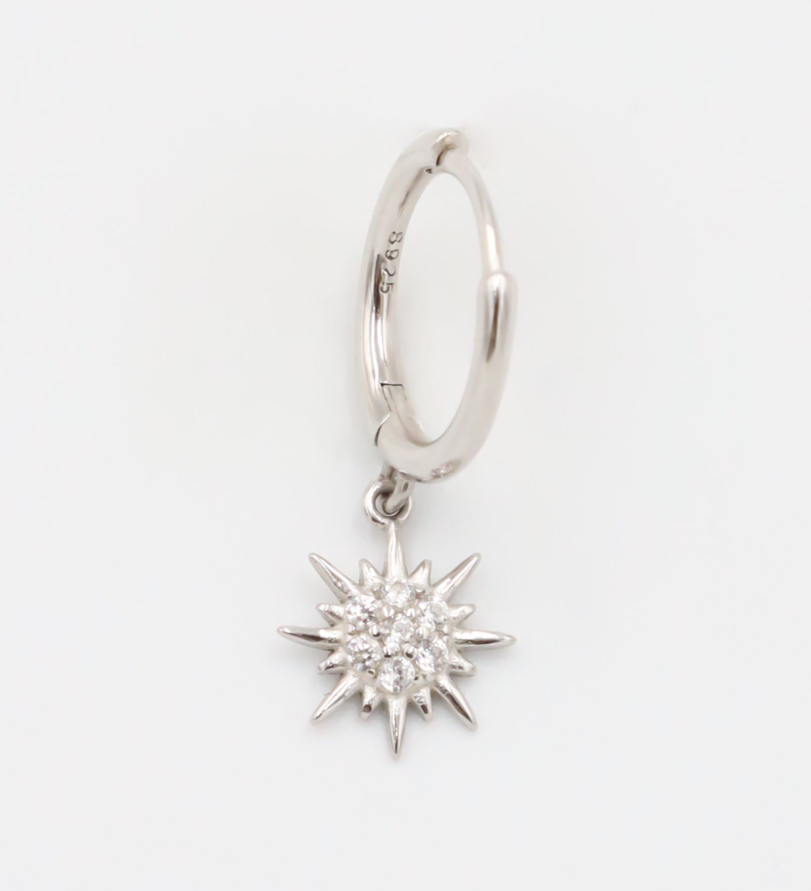 A silver hoop earring with a star-shaped charm attached to it, displayed against a white background.