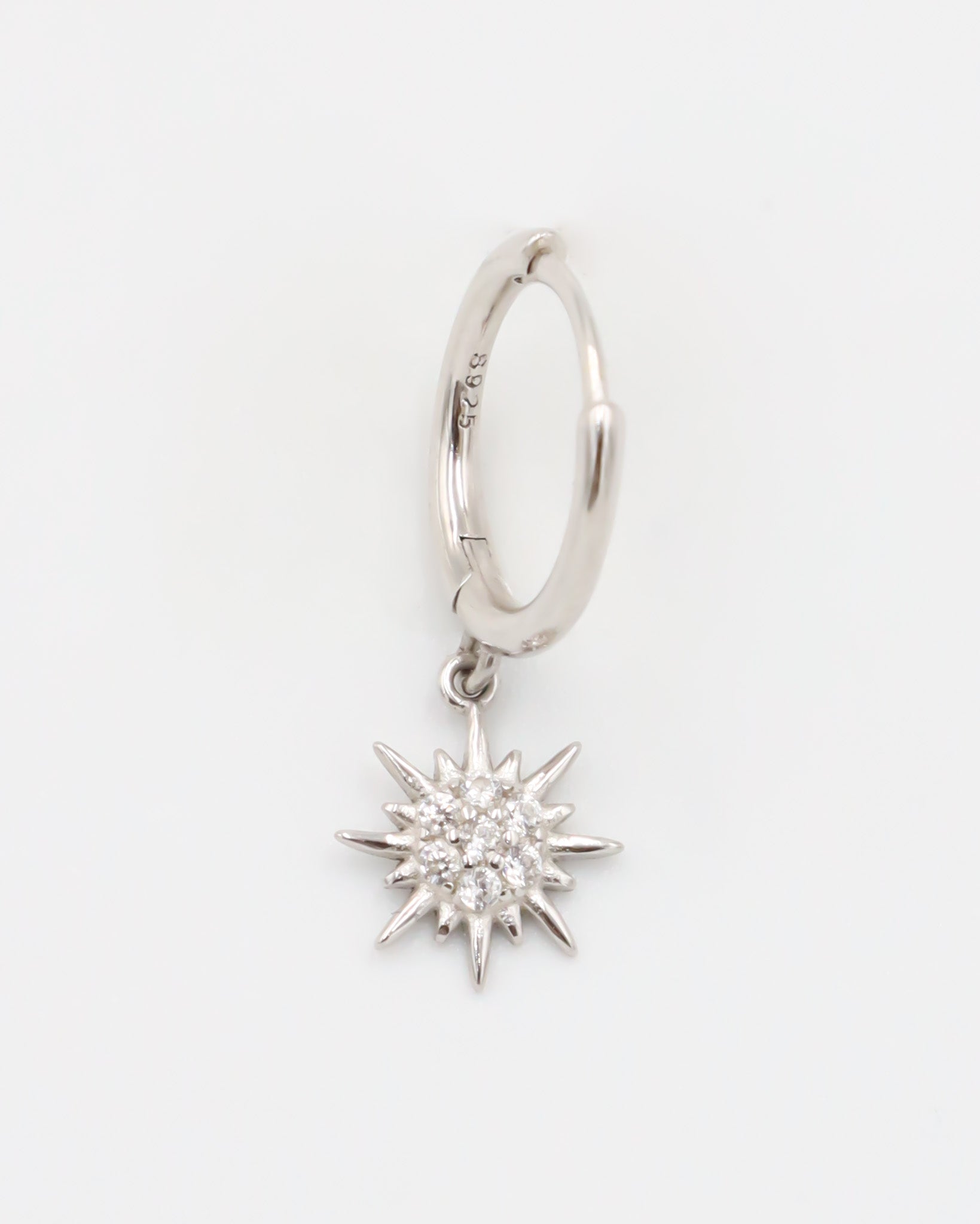 A silver hoop earring with a star-shaped charm attached to it, displayed against a white background.