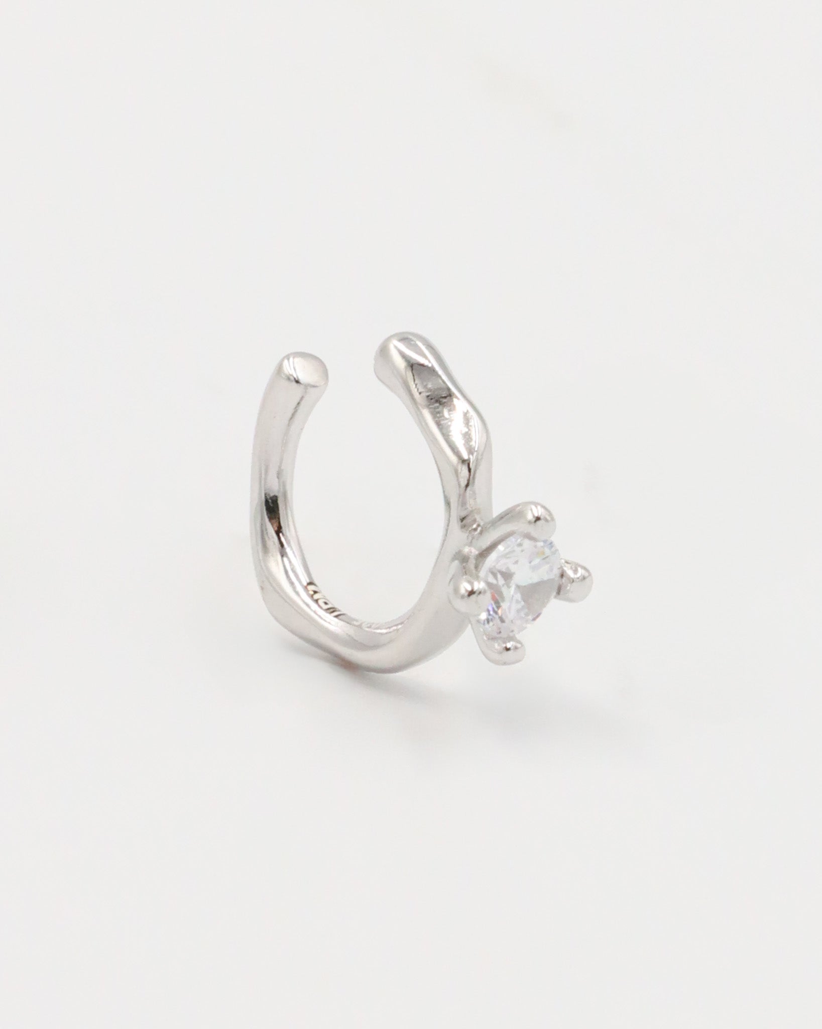 A silver ring with a round band and a central, square-shaped, transparent crystal embellishment.