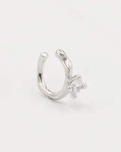 A silver ring with a round band and a central, square-shaped, transparent crystal embellishment.