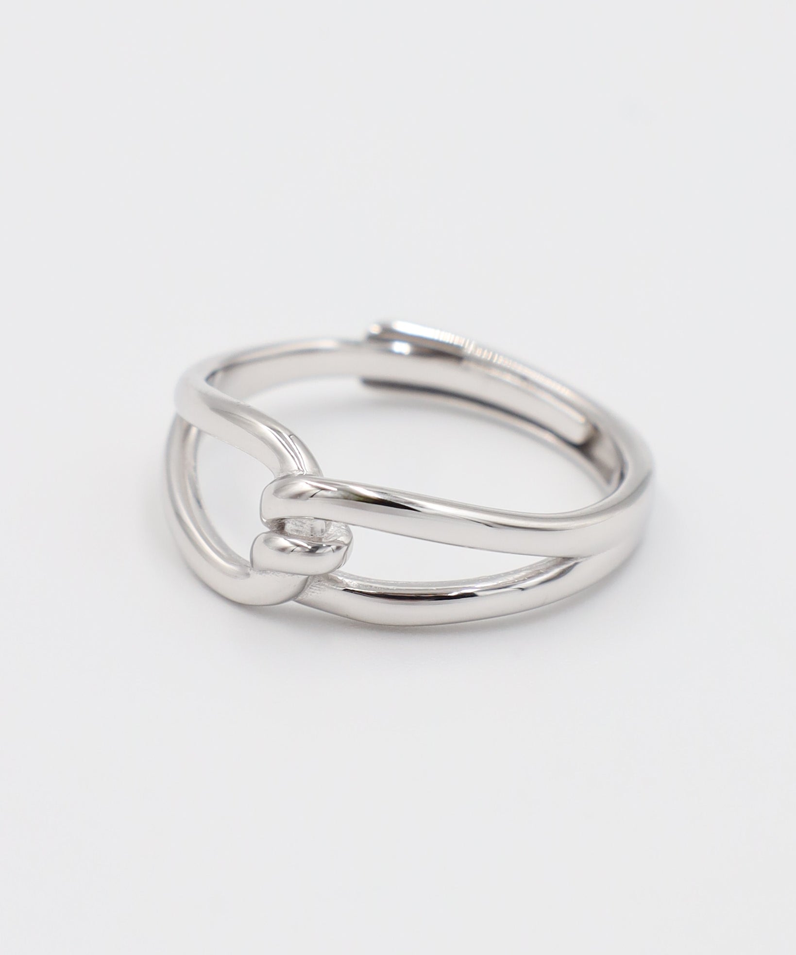 A simple silver ring with a unique design, featuring a knot-like pattern on a white background.