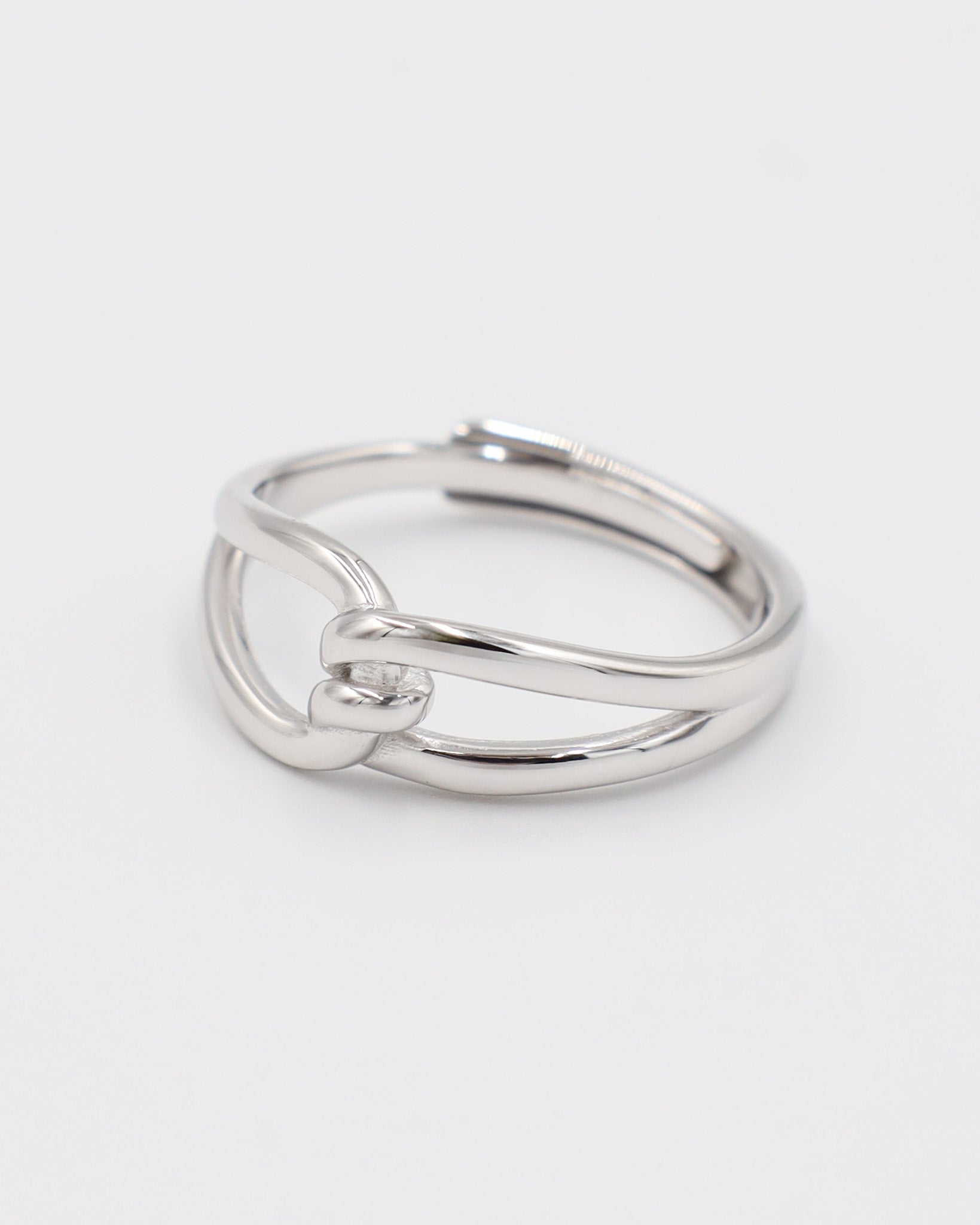 A simple silver ring with a unique design, featuring a knot-like pattern on a white background.