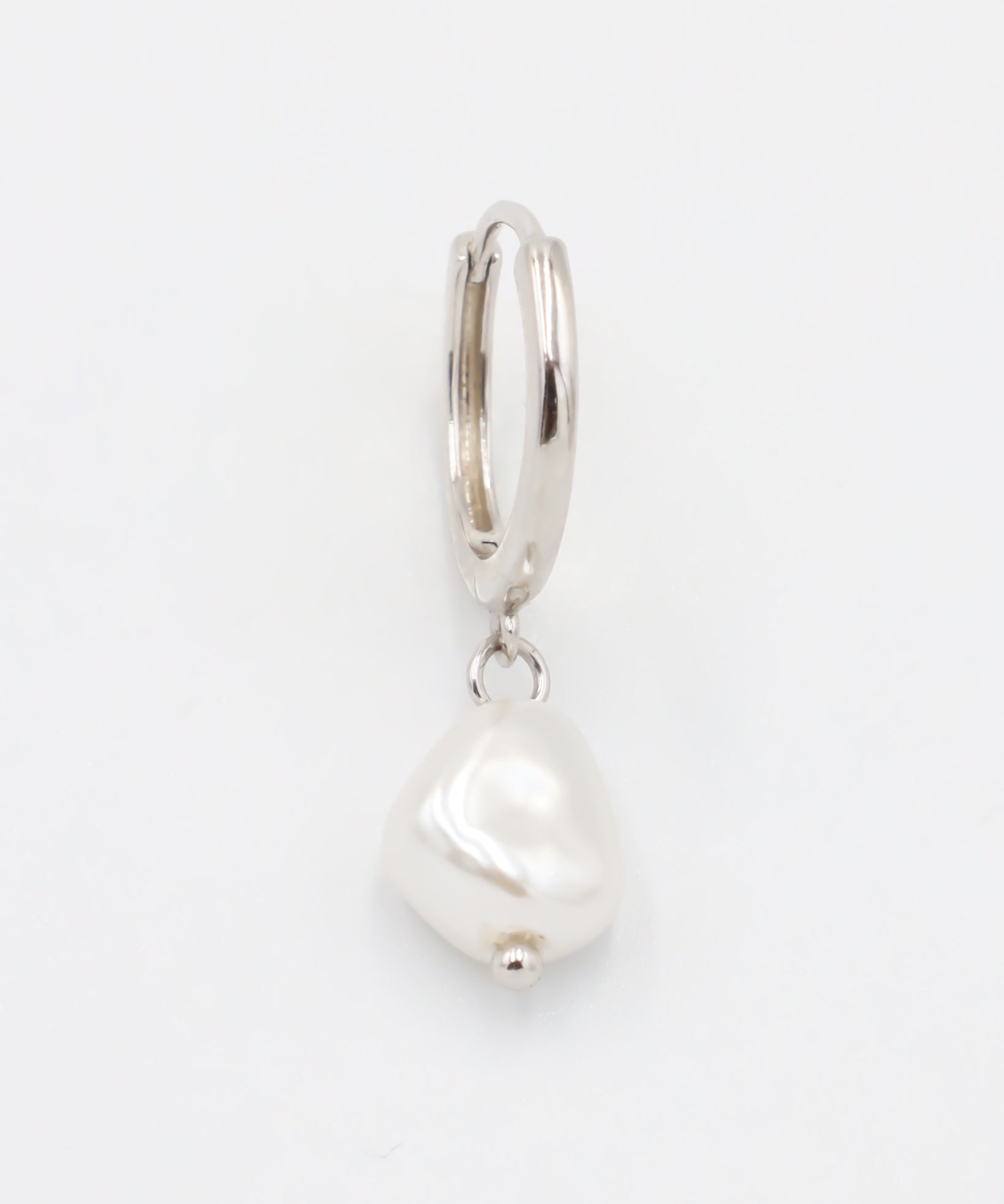 A silver-colored hoop earring with a white pearl charm attached to it.