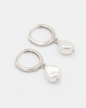 A silver-colored hoop earring with a white pearl charm attached to it.