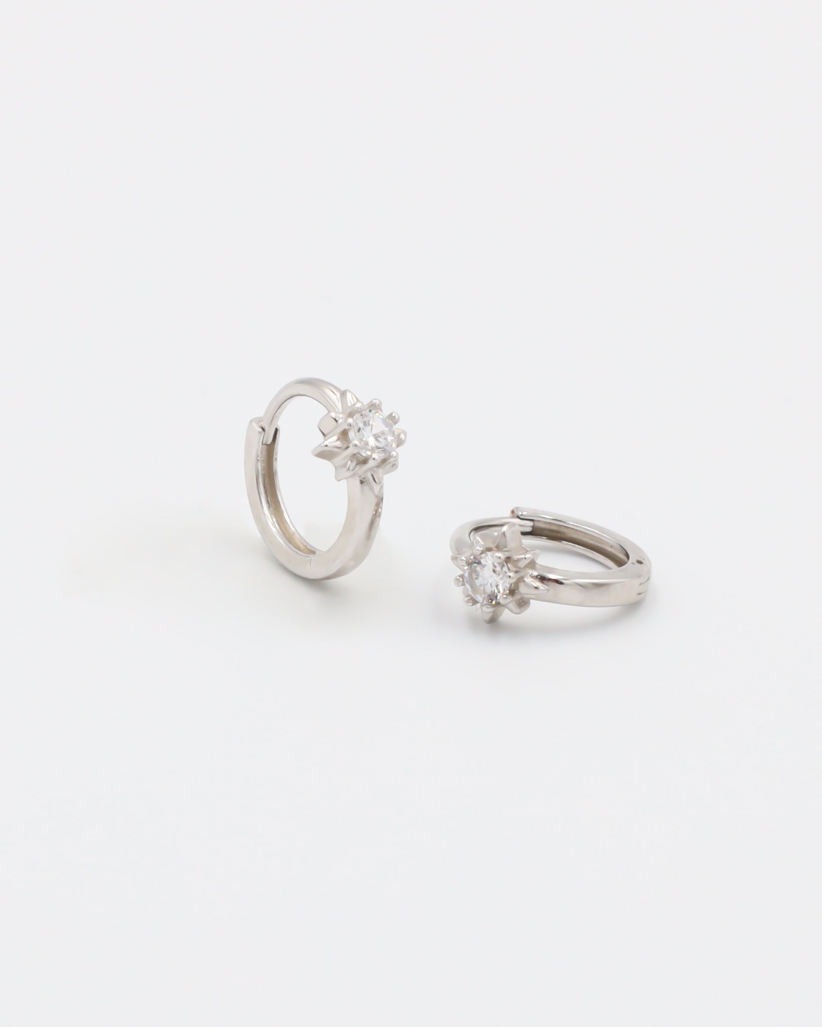 A silver hoop earring with a hinged clasp and no visible gemstone.