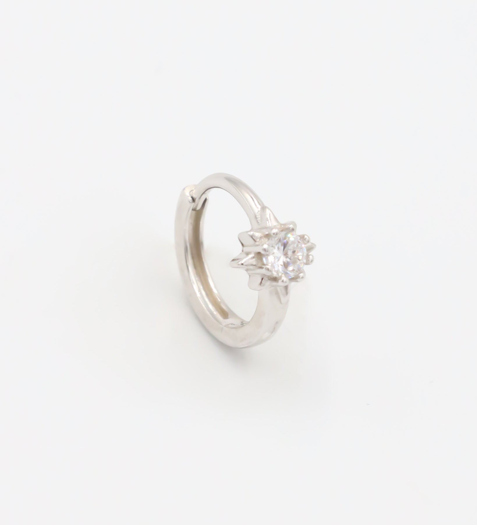 A silver hoop earring with a hinged clasp and no visible gemstone.