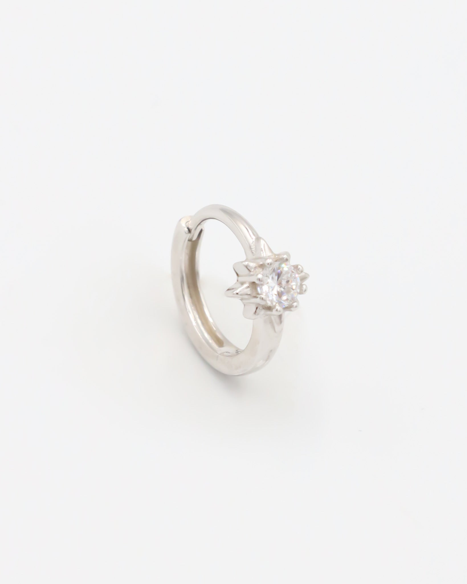 A silver hoop earring with a hinged clasp and no visible gemstone.