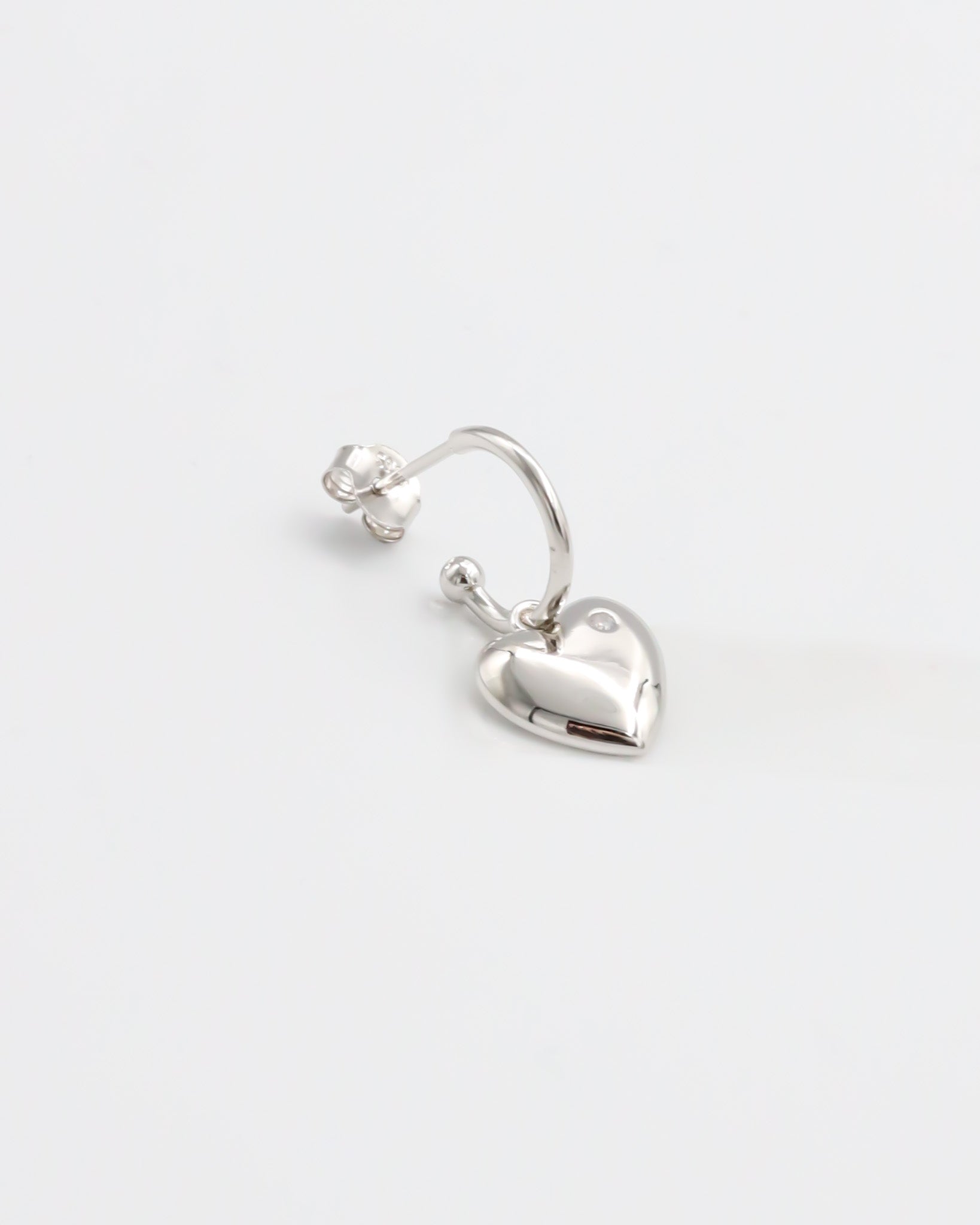 A pair of silver heart-shaped stud earrings with butterfly clasps on a white background.