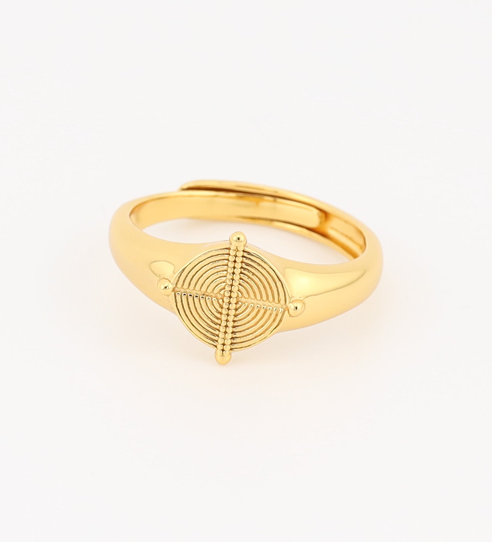 Gold ring with a circular design on a light beige background