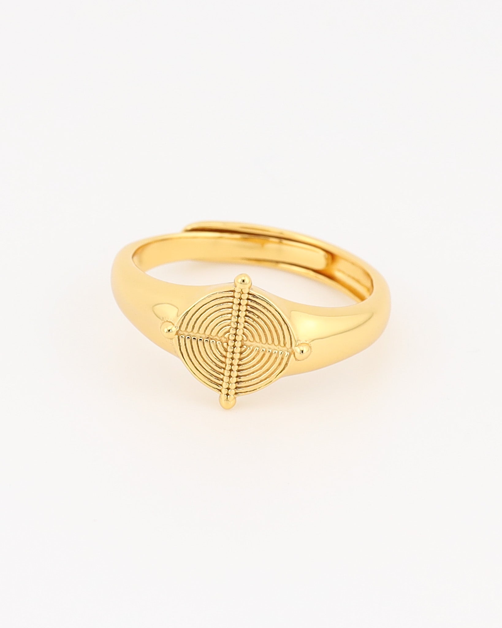 Gold ring with a circular design on a light beige background