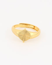 Gold ring with a circular design on a light beige background