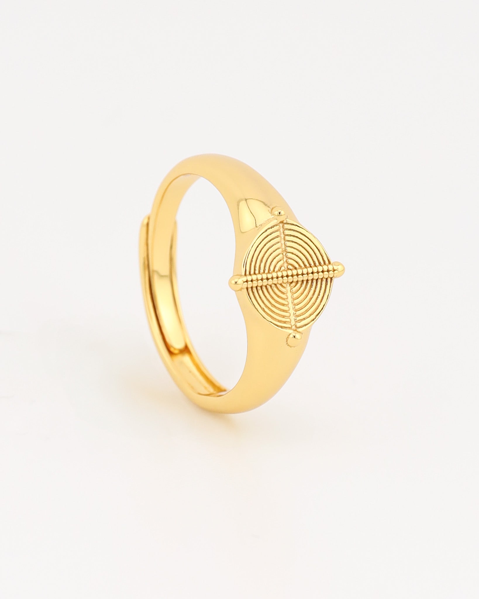 Gold ring with geometric design on a light beige background