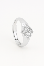 Silver ring with geometric design on a light beige background