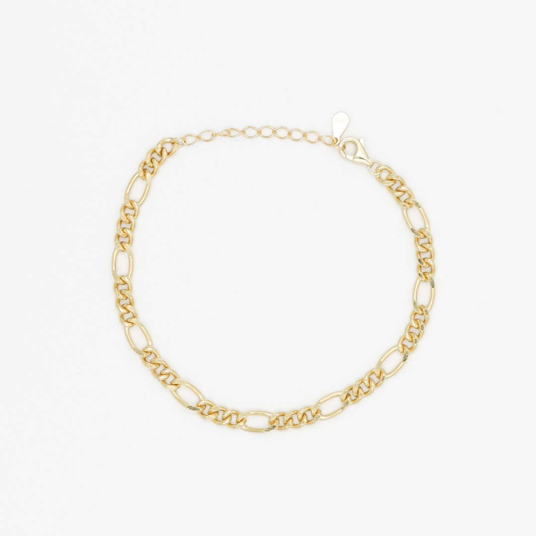 A gold-colored bracelet laid out on a plain surface.
