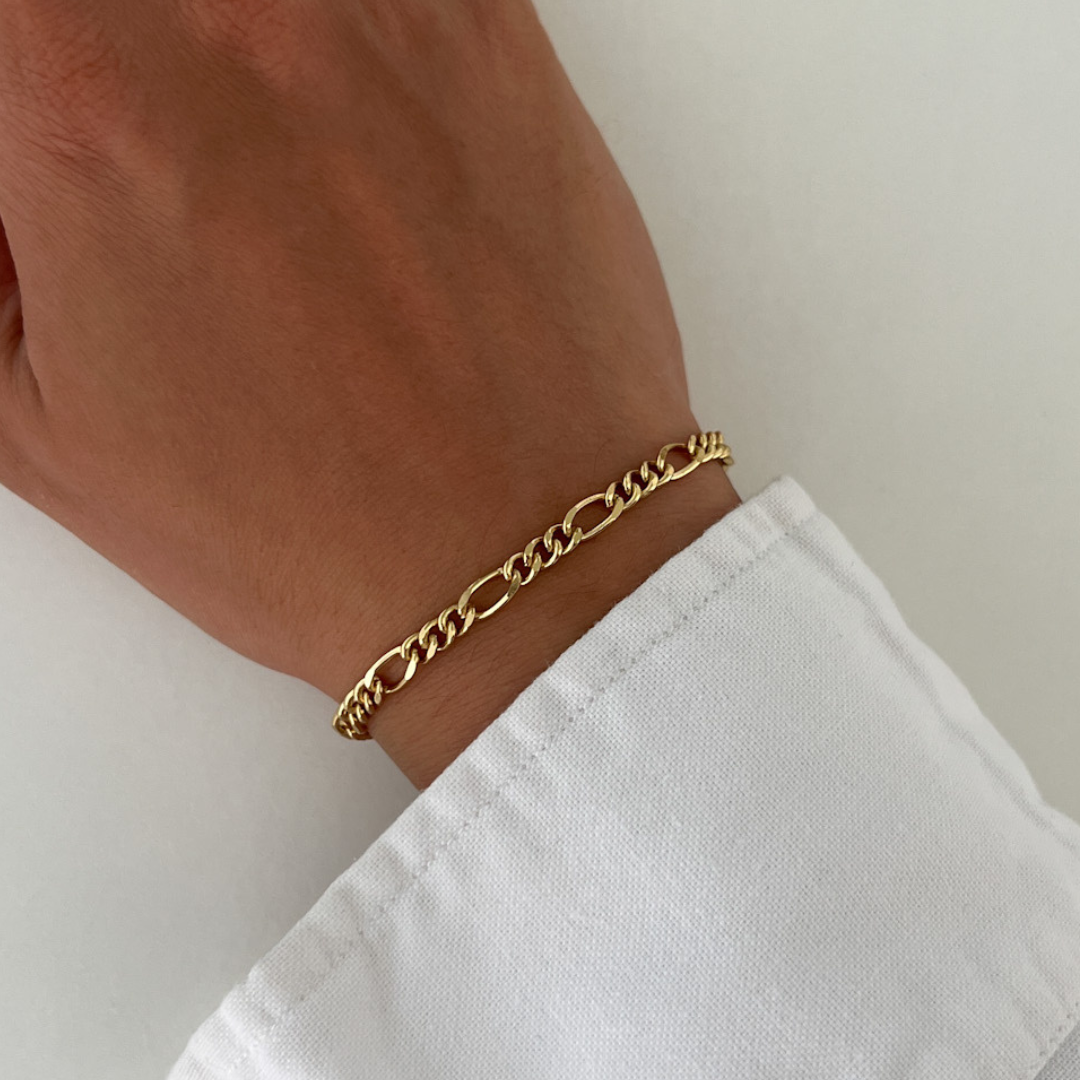 Close-up of a wrist wearing the Autumn gold bracelet with a chunky chain design, styled with a white long-sleeve shirt.