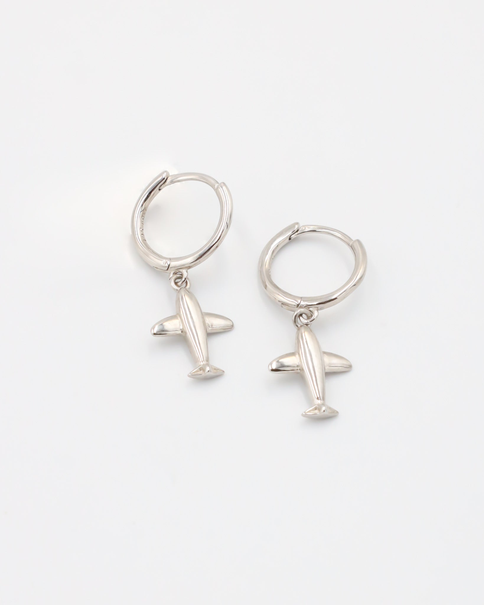 A silver hoop earring with a small airplane charm attached to it, displayed against a white background.