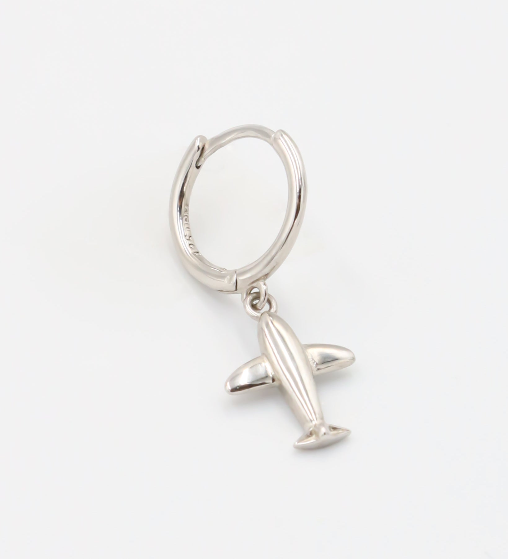 A silver hoop earring with a hinged clasp and a small airplane charm attached to it.