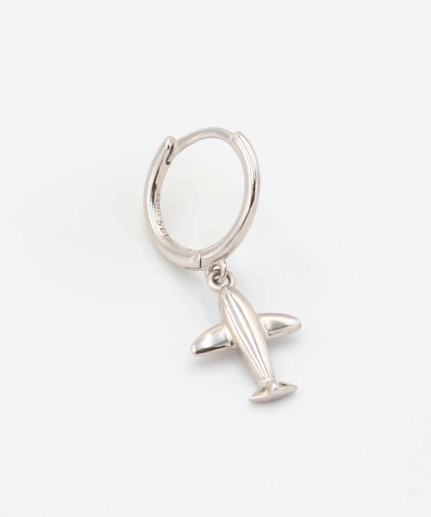 A silver hoop earring with a hinged clasp and a small airplane charm attached to it.