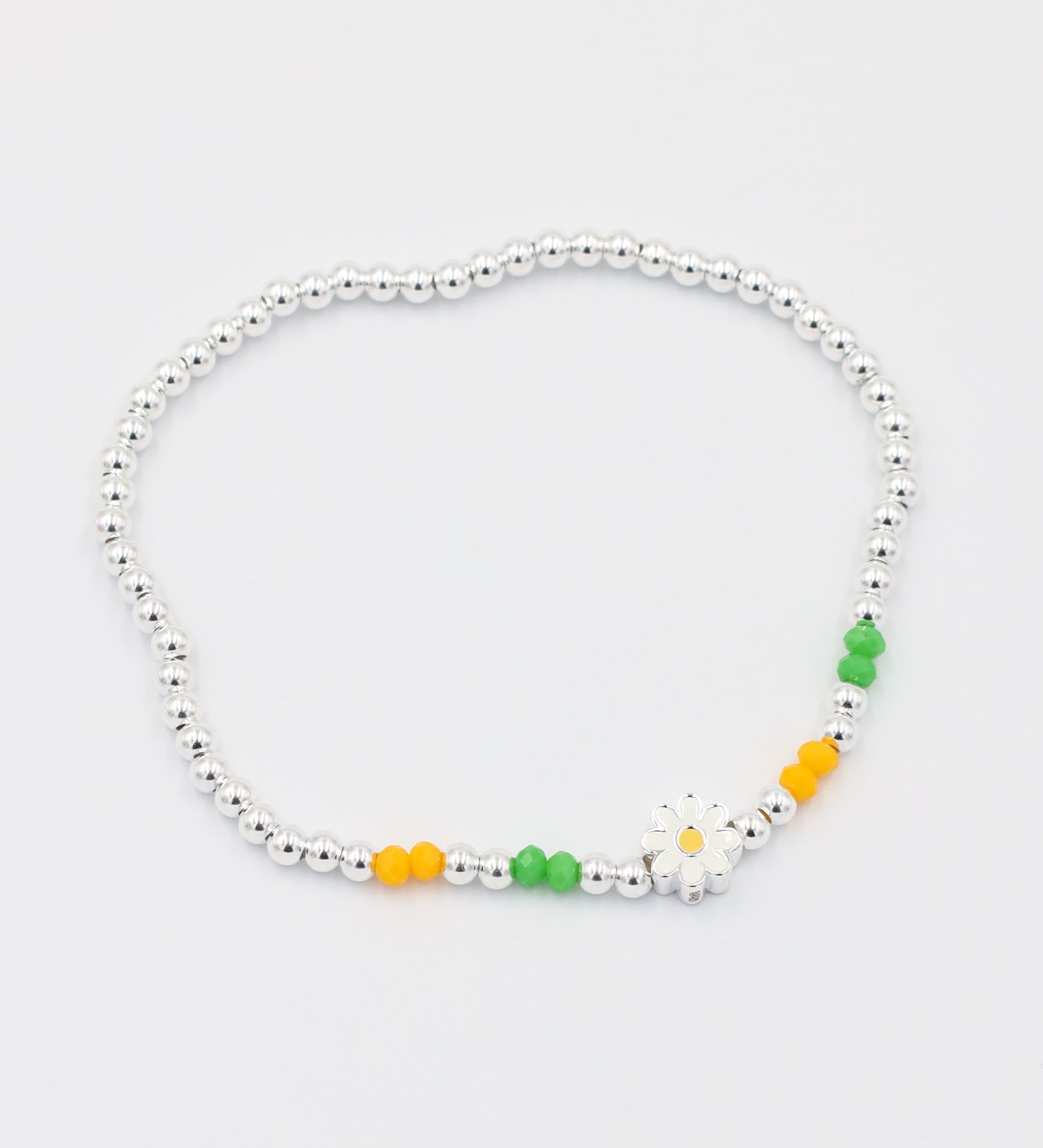 Front view of the adjustable Azalea bracelet made of 925 sterling silver and elastic, featuring yellow and green beads with a daisy charm.