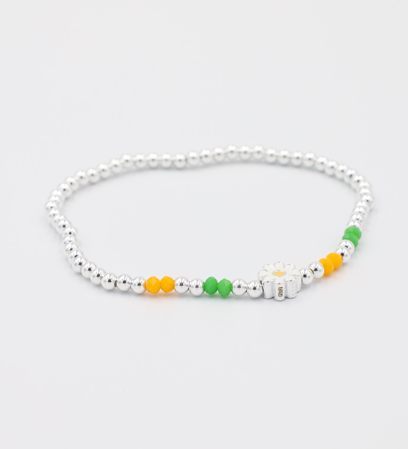 Top view of the adjustable 925 sterling silver Azalea bracelet with green and yellow beads, and a daisy charm.
