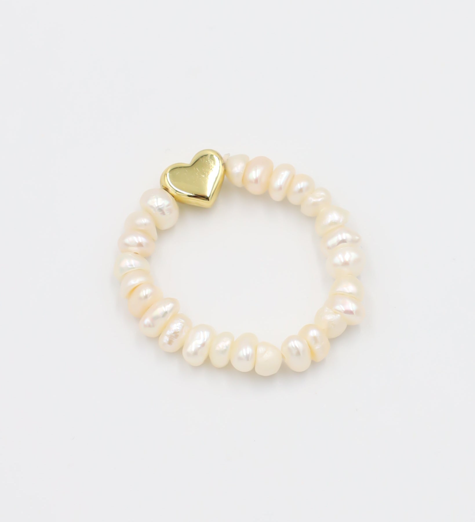 A bracelet with white pearls and a gold heart-shaped charm