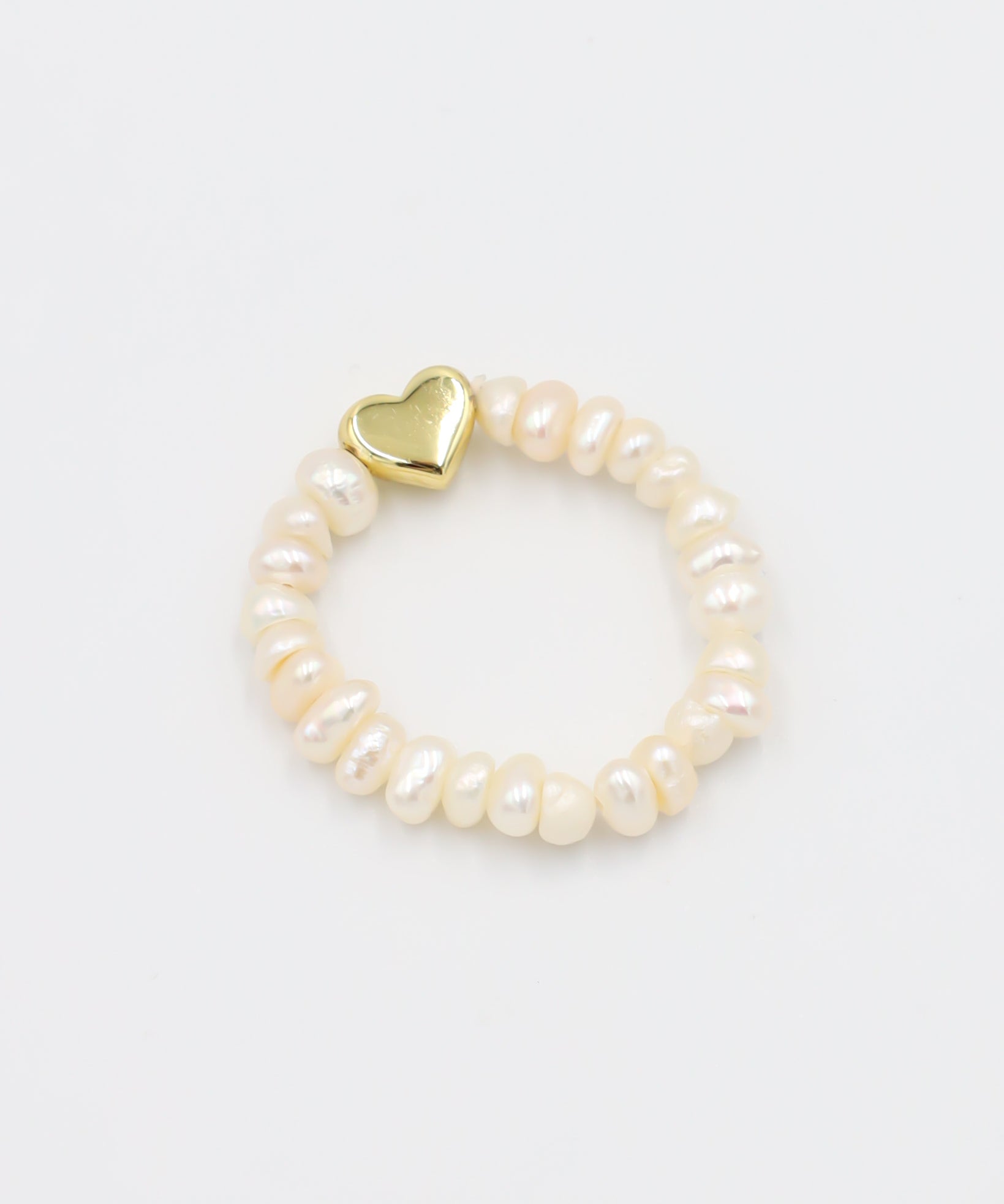A bracelet with white pearls and a gold heart-shaped charm
