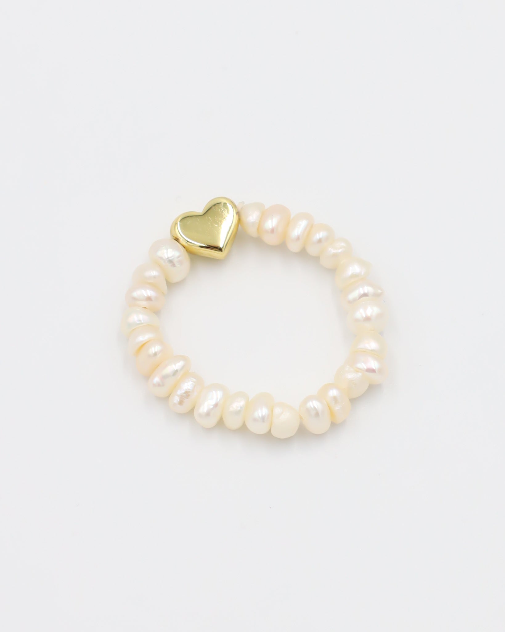 A bracelet with white pearls and a gold heart-shaped charm