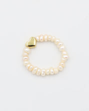 A bracelet with white pearls and a gold heart-shaped charm