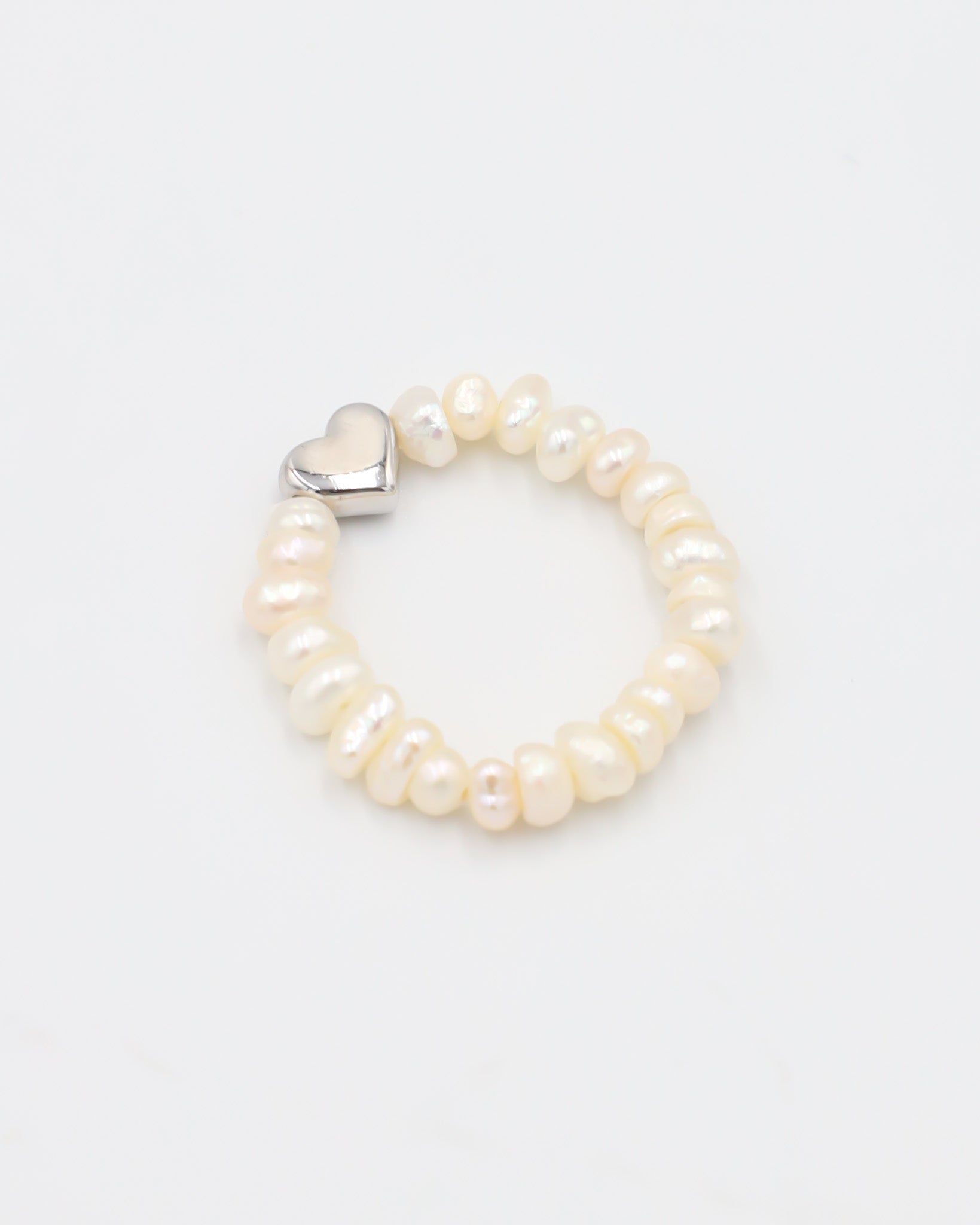 A ring bracelet with a heart-shaped clasp and white pearl-like beads.