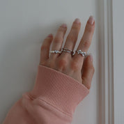 A silver ring with a heart-shaped clasp and white pearl-like beads worn on a hand.