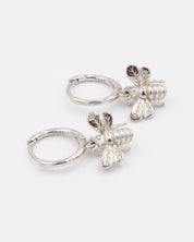 A silver hoop earring with a bee charm attached to it.
