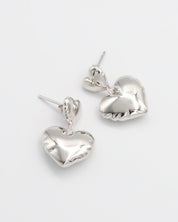 A pair of silver heart-shaped stud earrings with butterfly clasps on a white background