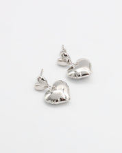 A pair of silver heart-shaped stud earrings with butterfly clasps on a white background