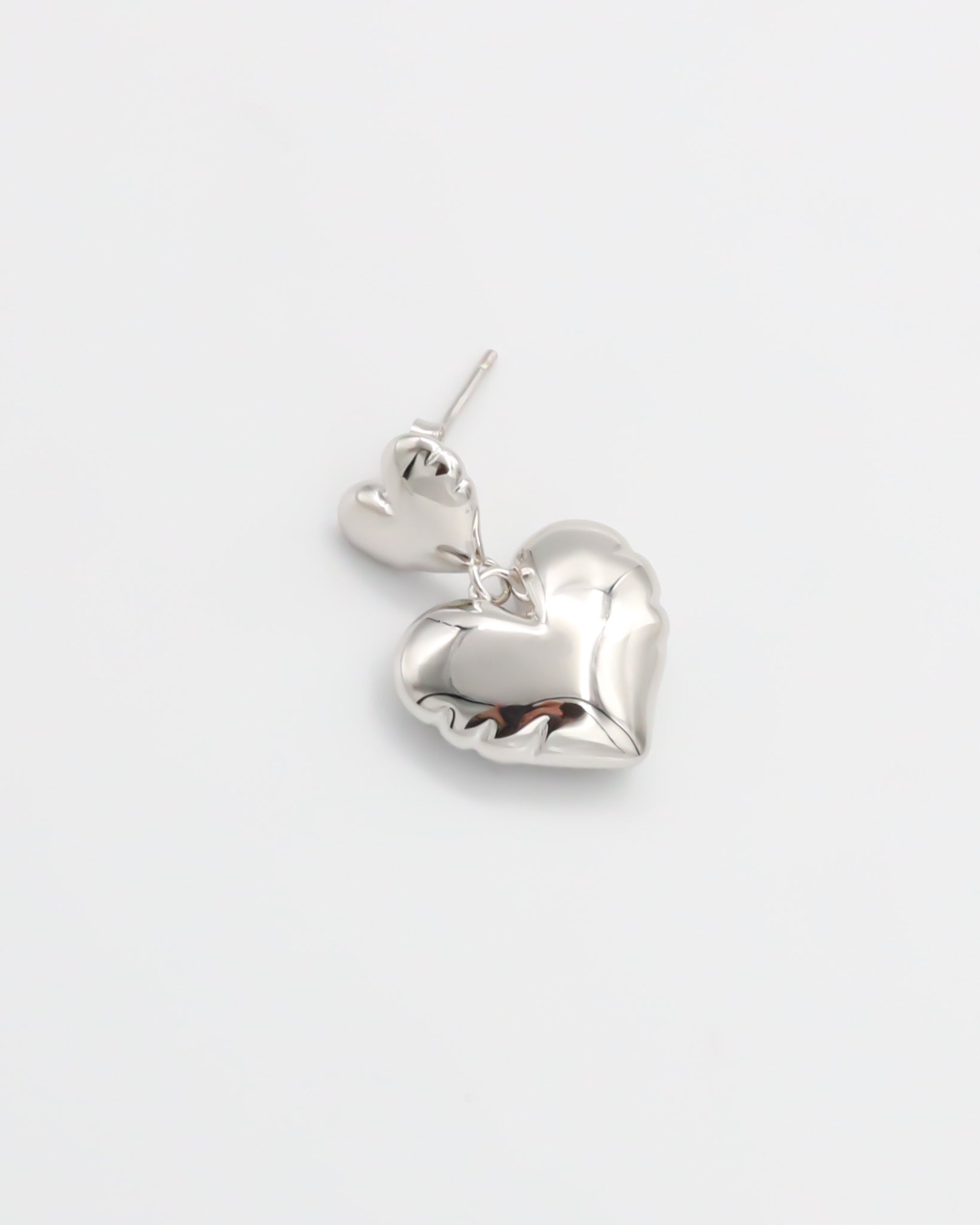 A pair of silver heart-shaped stud earrings with butterfly clasps on a white background