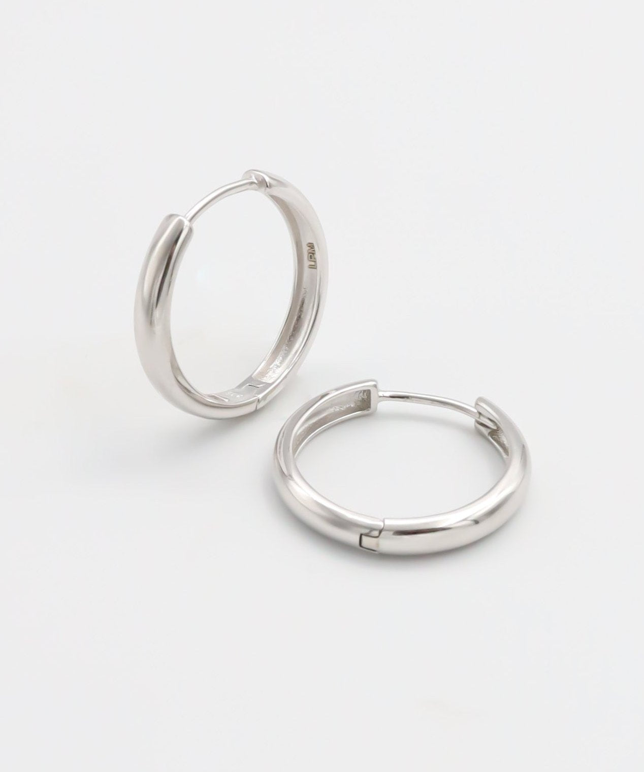 A pair of silver hoop earrings with a hinged clasp, displayed on a white background.