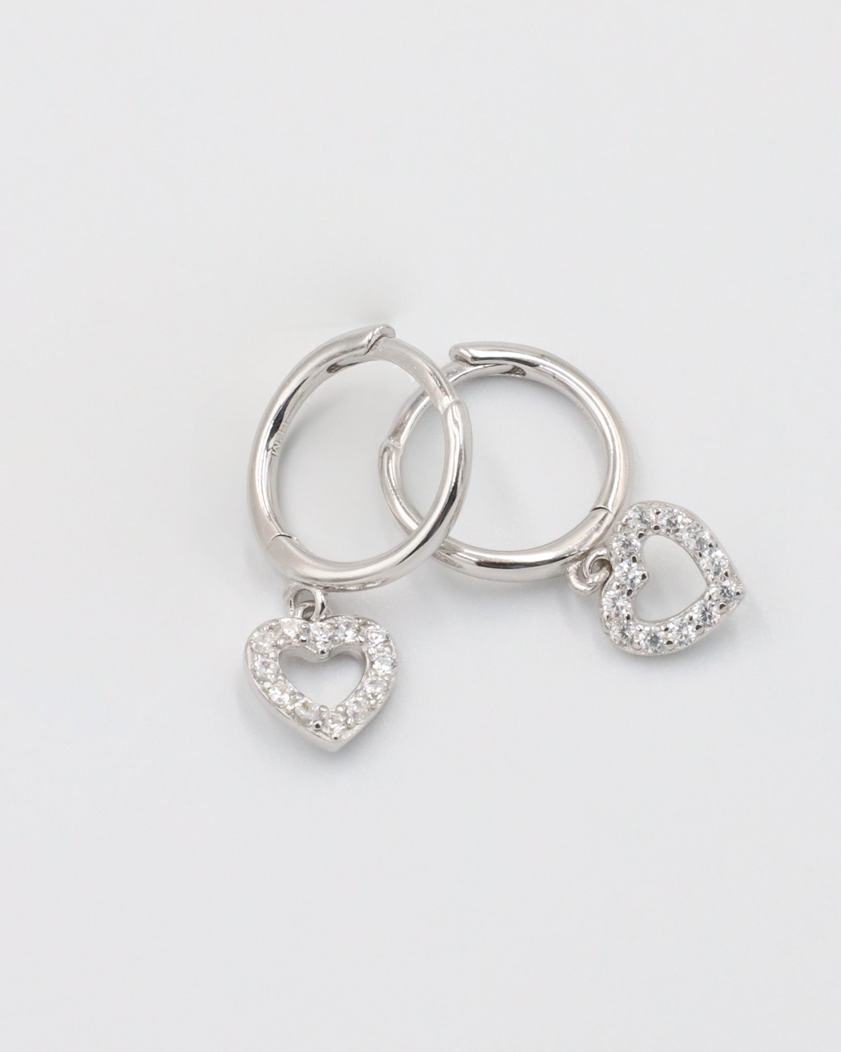 Silver hoop earrings with heart and 'O' charm on white background