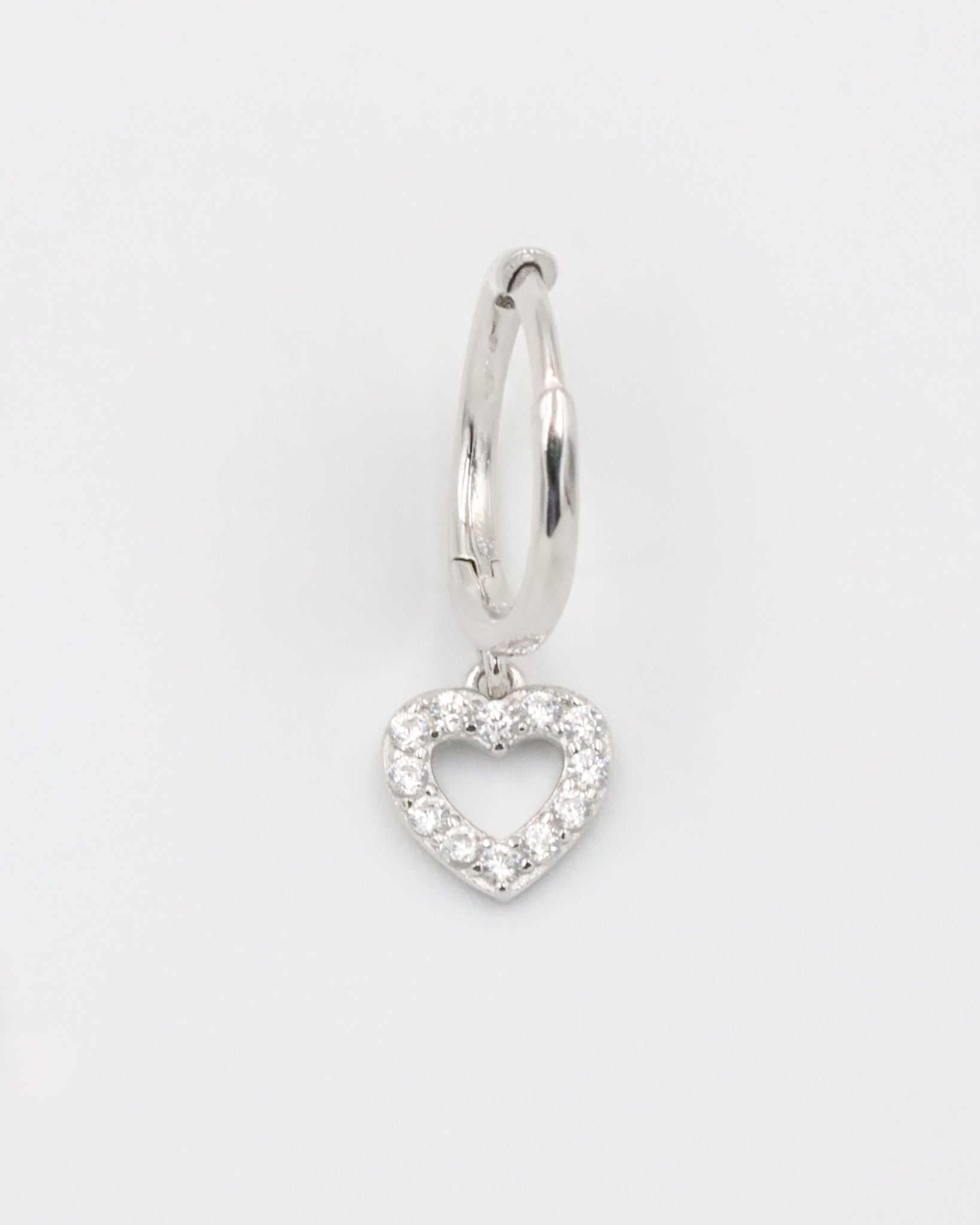 A silver hoop earring with a heart-shaped charm hanging from it, displayed against a white background.