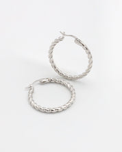 A pair of silver hoop earrings with a twist pattern on a white background