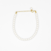 A gold-colored necklace featuring a series of size large pearl beads and a small gold chain.