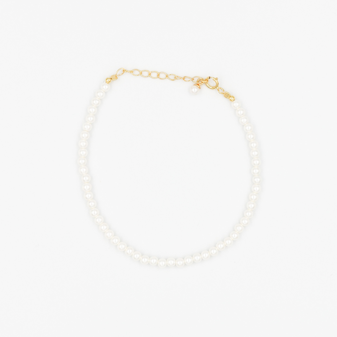 A gold-colored necklace featuring a series of size medium pearl beads and a small gold chain.