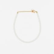 A gold-colored necklace featuring a series of size small pearl beads and a small gold chain.
