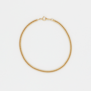 A gold-colored necklace laid out on a plain background.