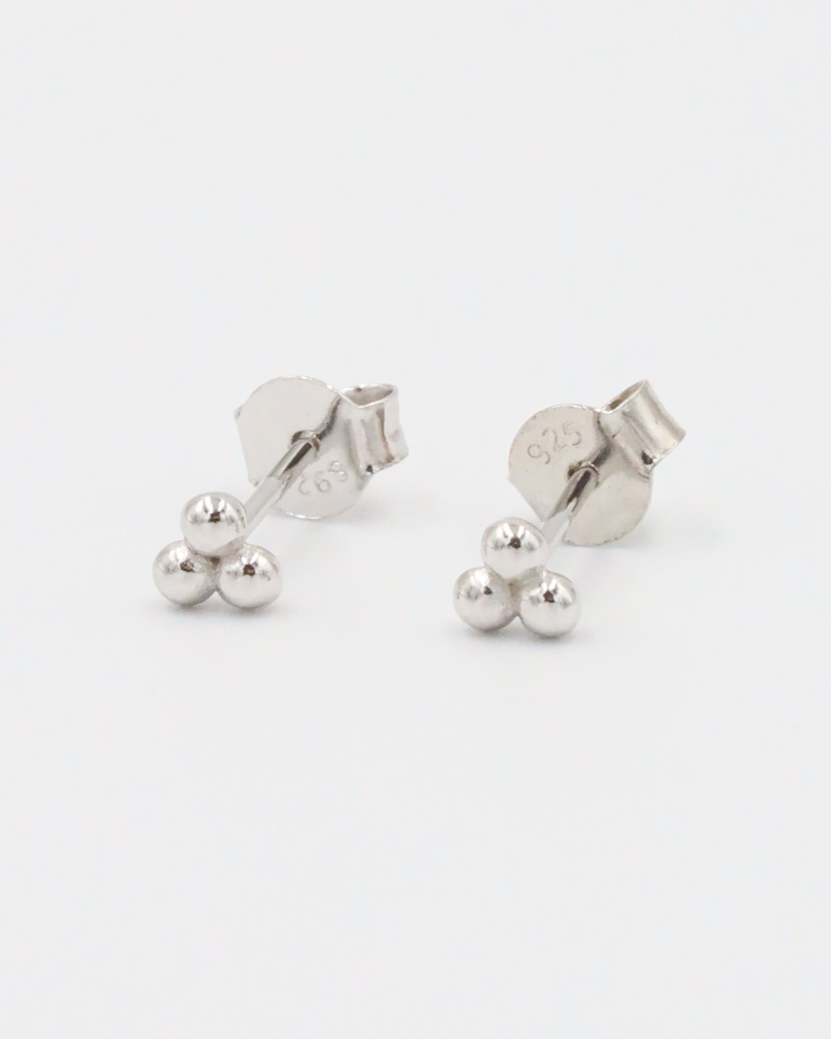 A single silver stud earring with a butterfly clasp, featuring a small spherical design.