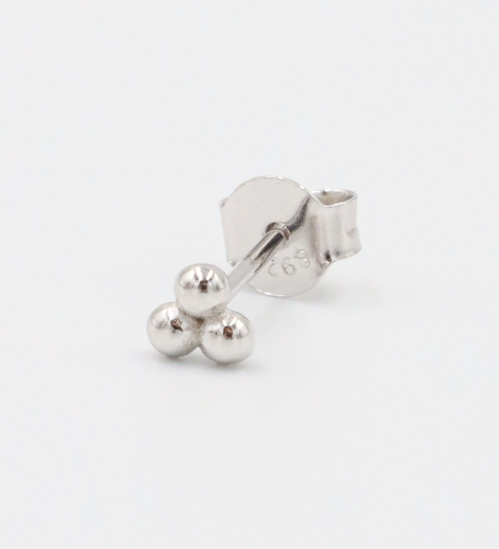 A single silver stud earring with a butterfly clasp, featuring a small spherical design.