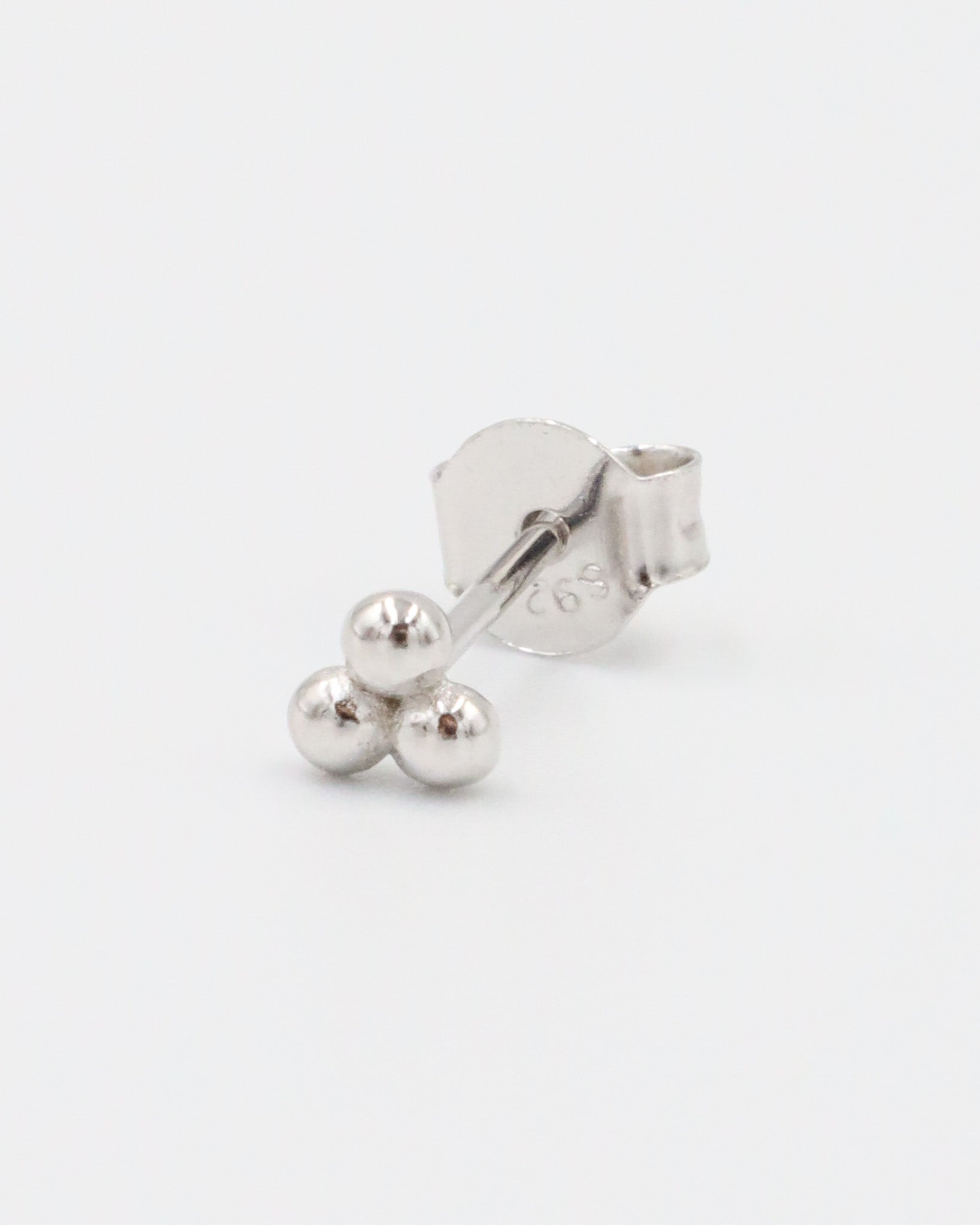 A single silver stud earring with a butterfly clasp, featuring a small spherical design.