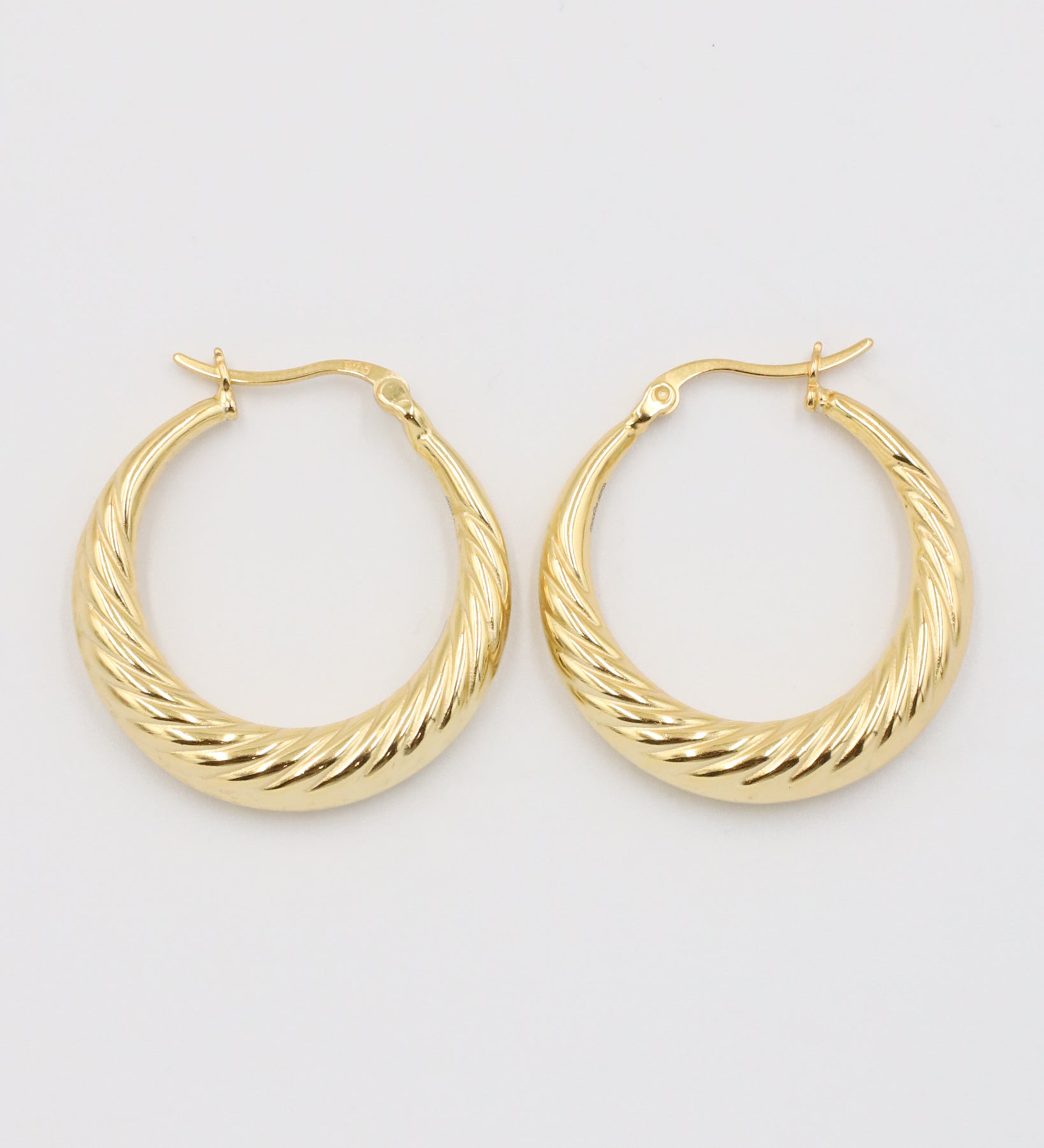 A pair of gold-colored hoop earrings with a latch back clasp on a white background.