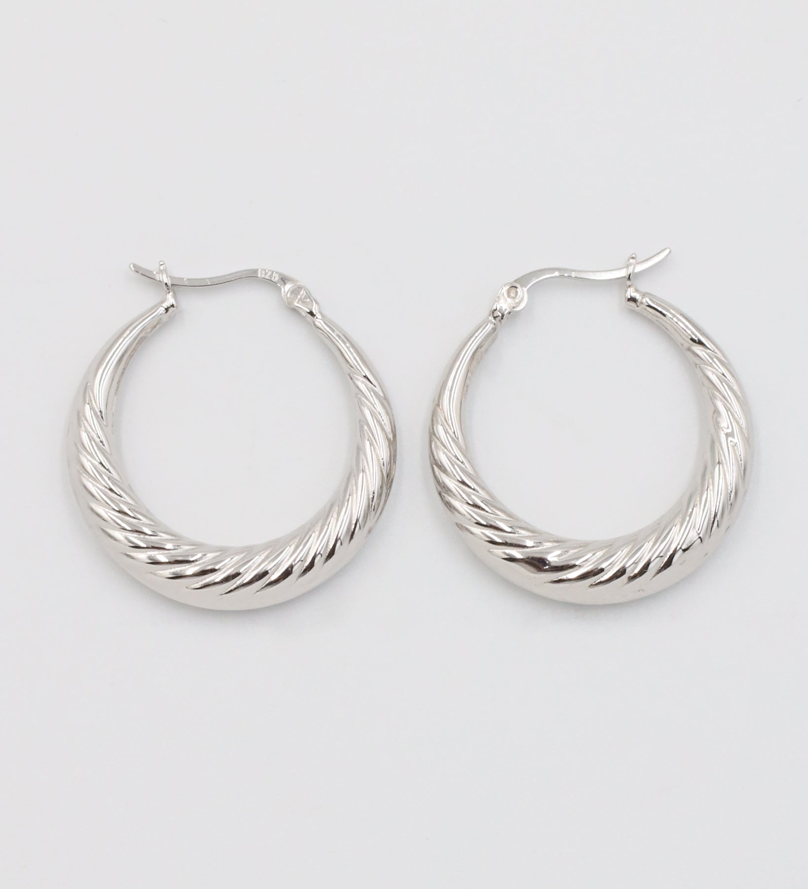 A pair of silver-colored hoop earrings with a latch back clasp.