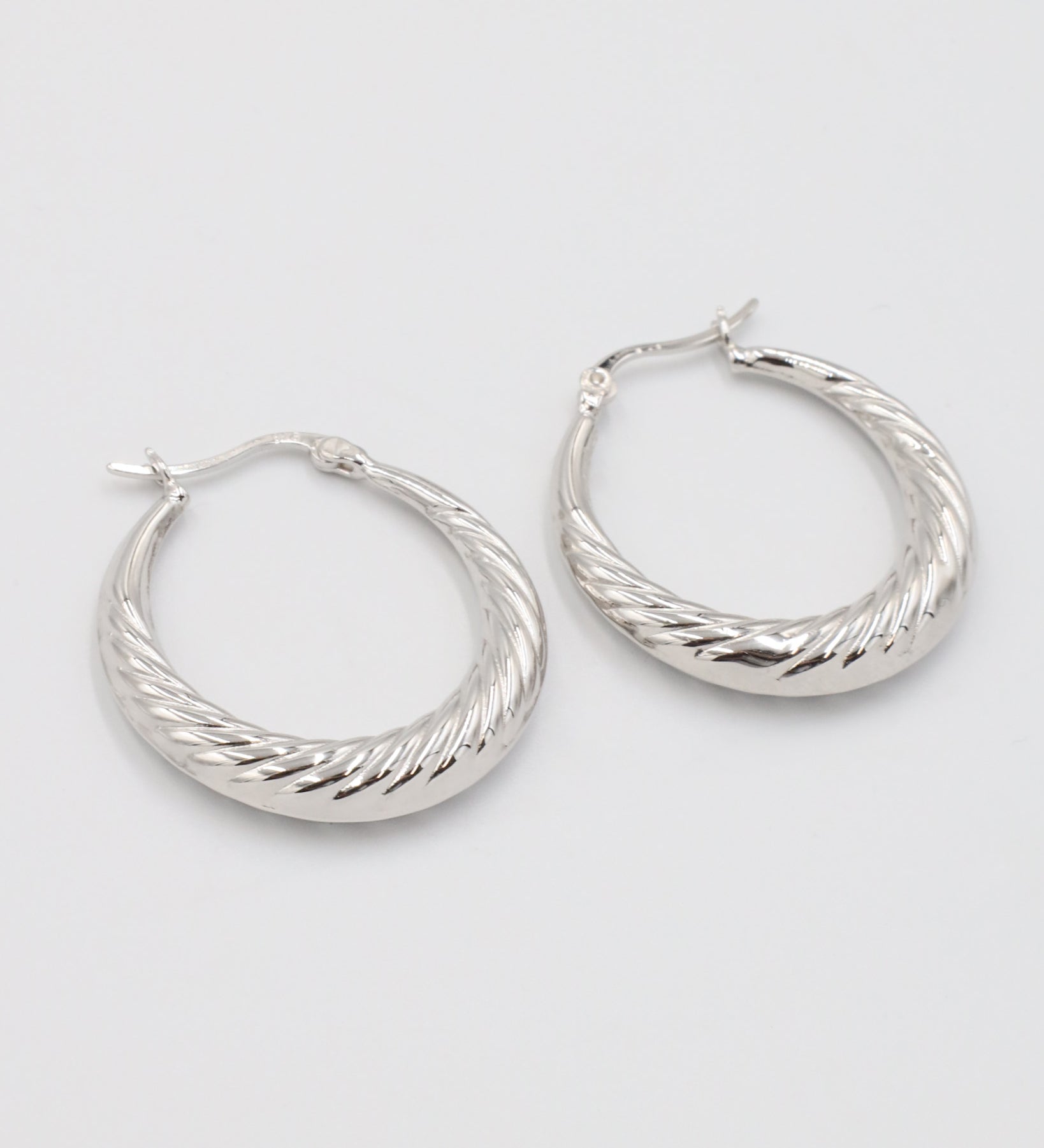 A pair of silver-colored hoop earrings with a latch back clasp.