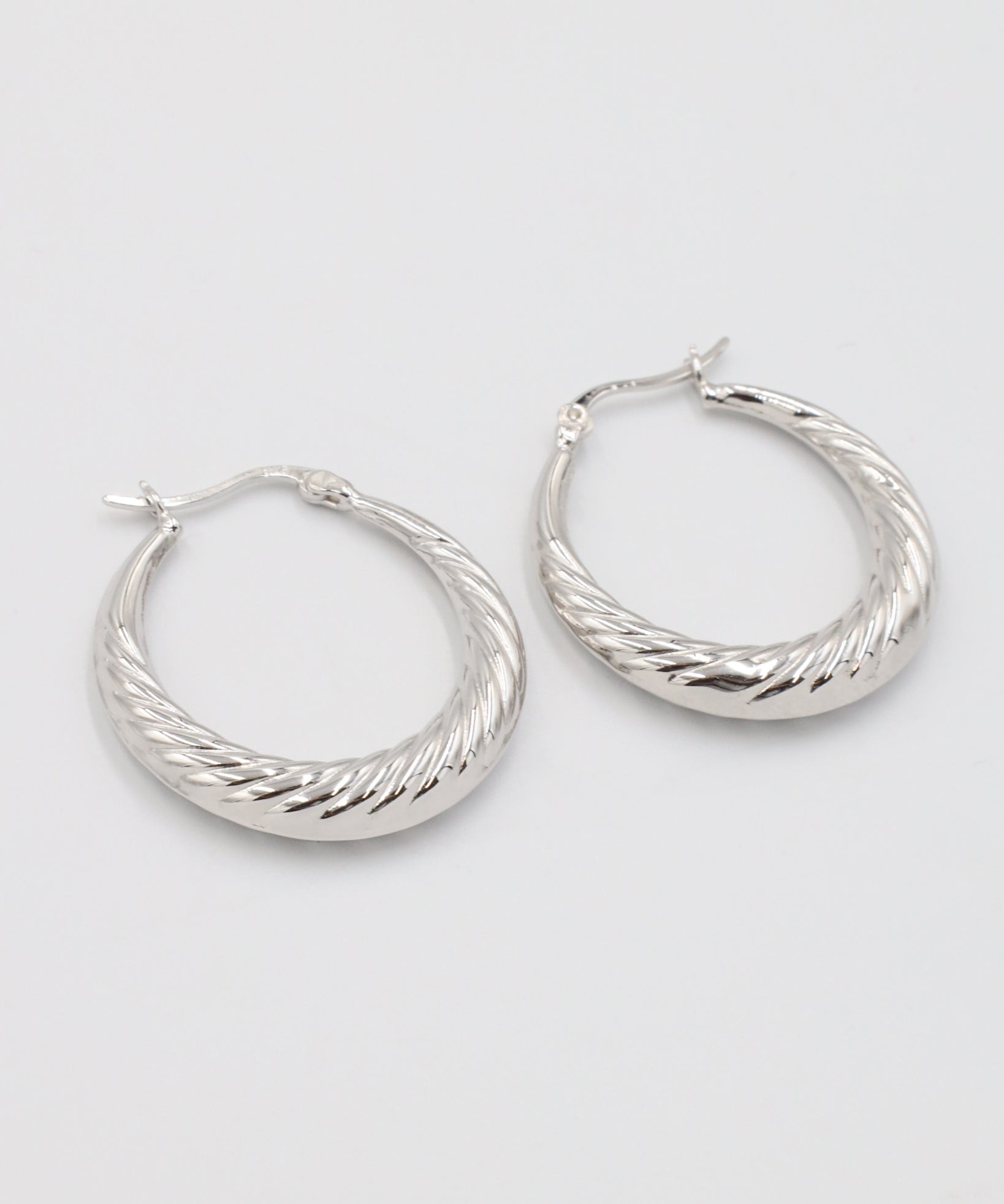 A pair of silver-colored hoop earrings with a latch back clasp.