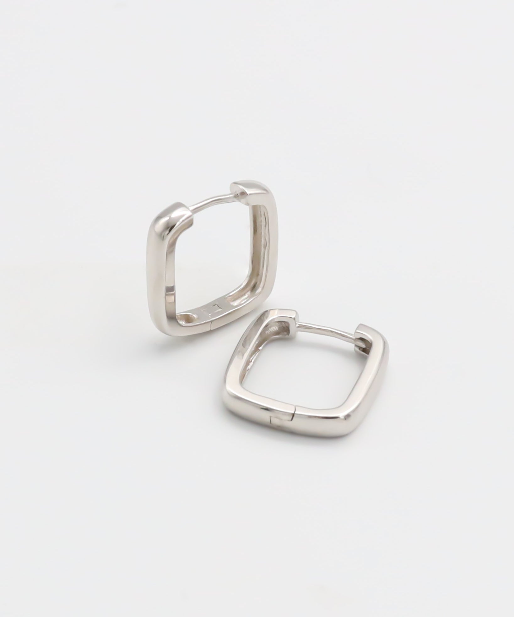 A pair of silver-colored hoop earrings with a hinged clasp, displayed against a white background.